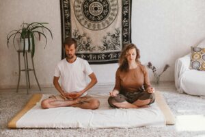 A serene atmosphere with two adults meditating indoors on a mat, embracing mindfulness.